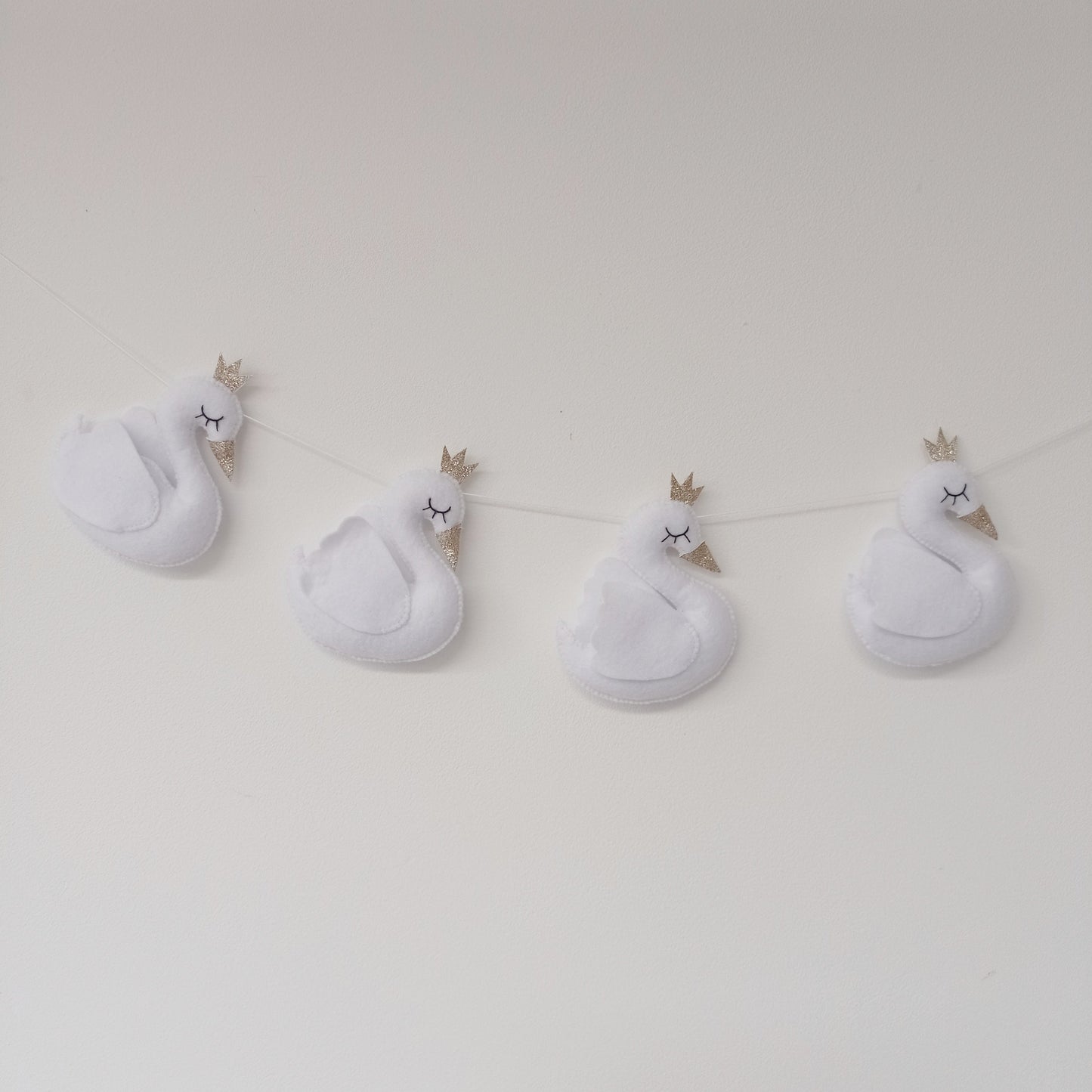 Guirlande cygnes blancs en feutrine avec couronnes dorées.