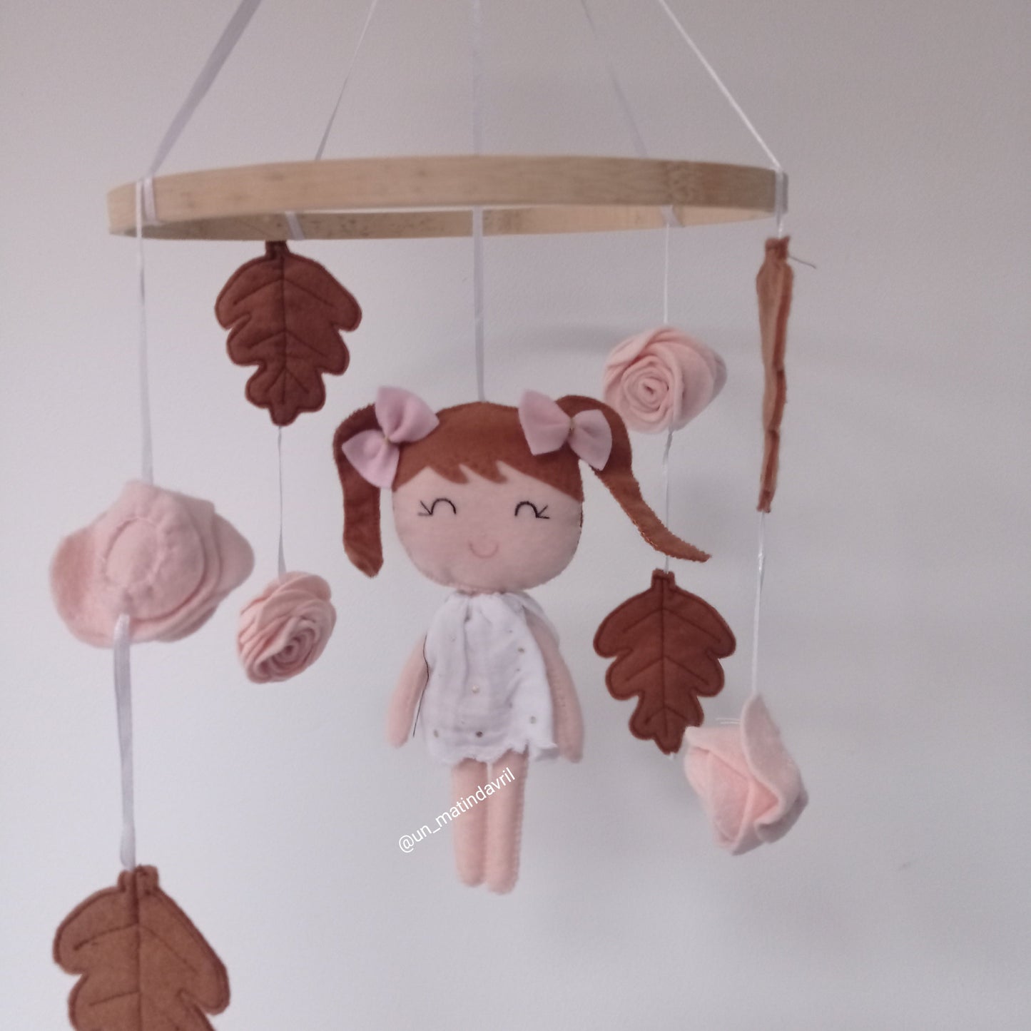 Mobile forêt composé d'une petite poupée en feutrine, de feuilles de chênes et de roses