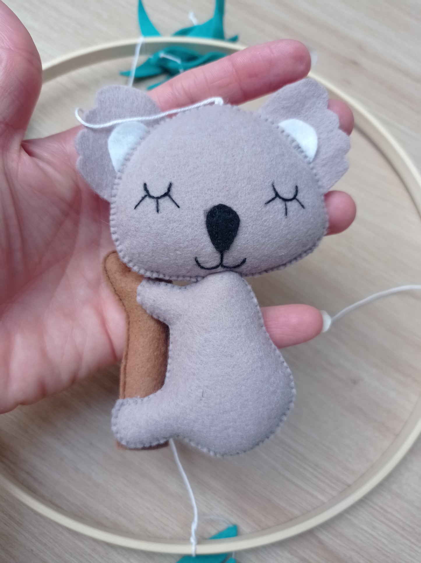 Koala gris en feutrine sur une branche d'arbre fait main.