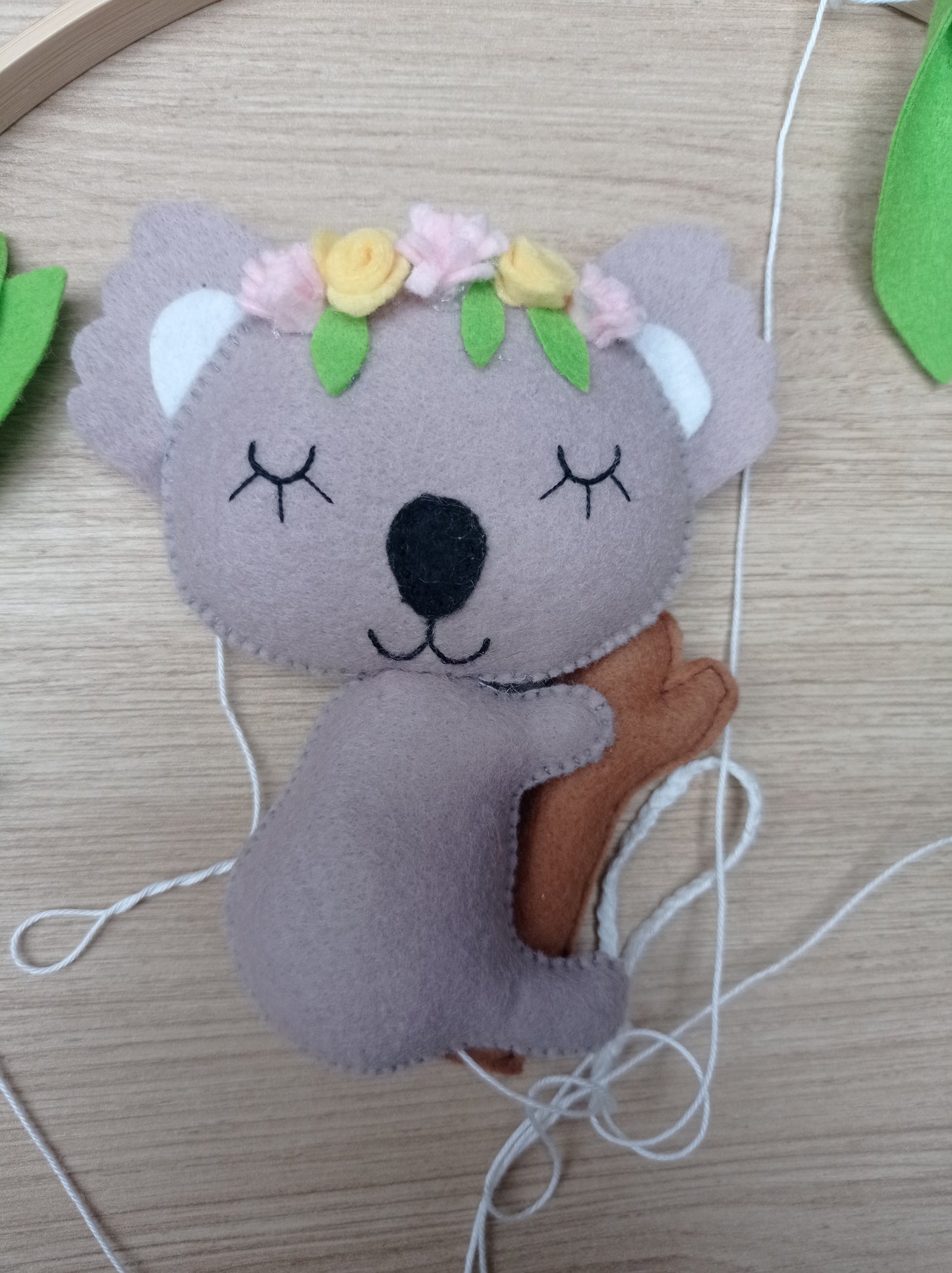 Koala fait main en feutrine avec la tête ornée d'une couronne de fleurs.