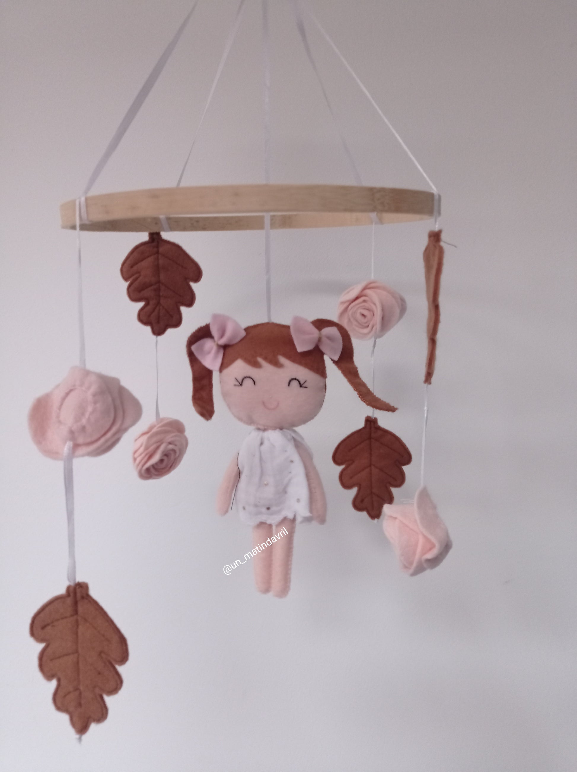 Mobile forêt composé d'une petite poupée en feutrine, de feuilles de chênes et de roses