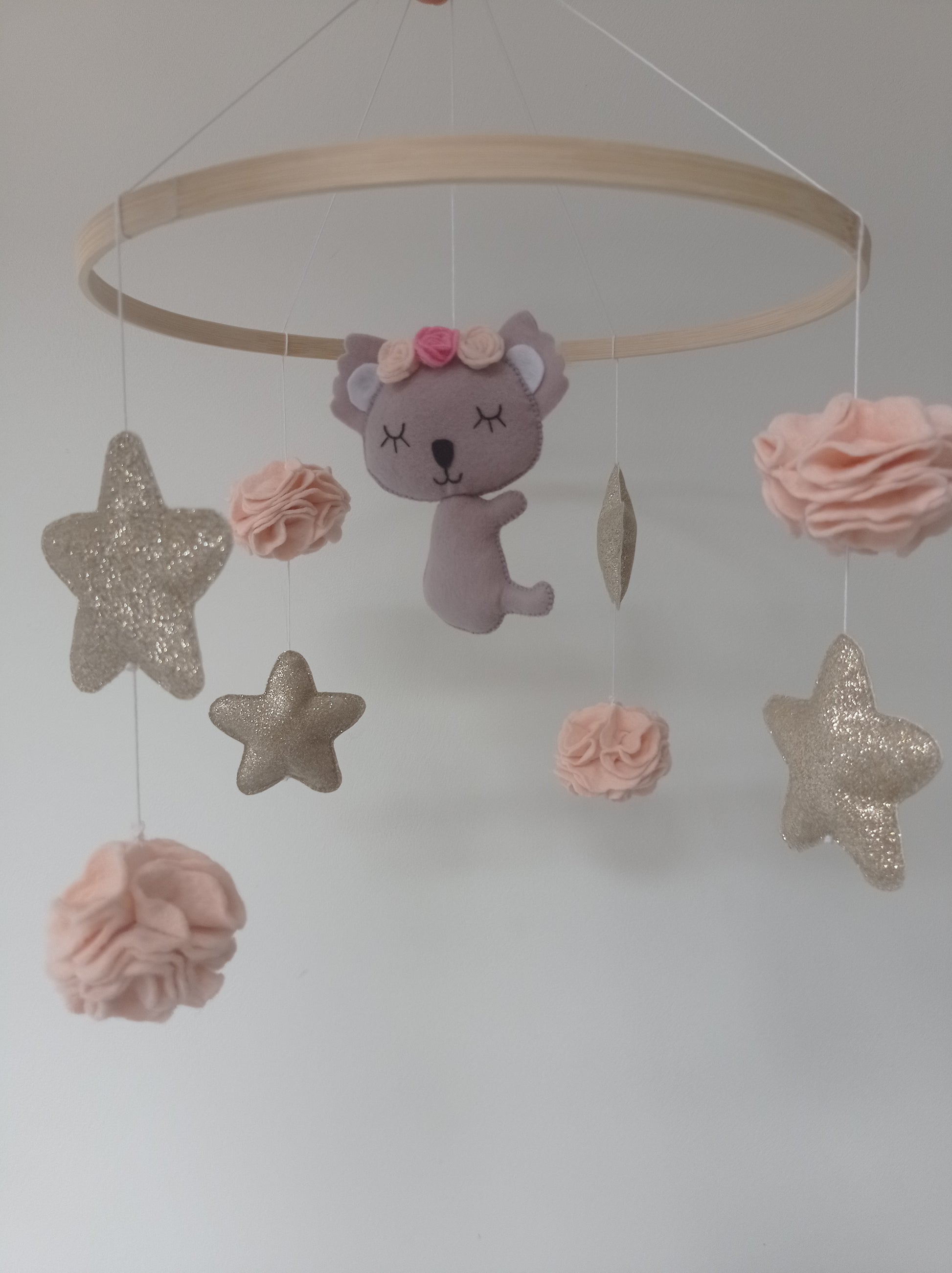 Mobile koala en feutrine, étoiles dorées et pompons fleurs rose.